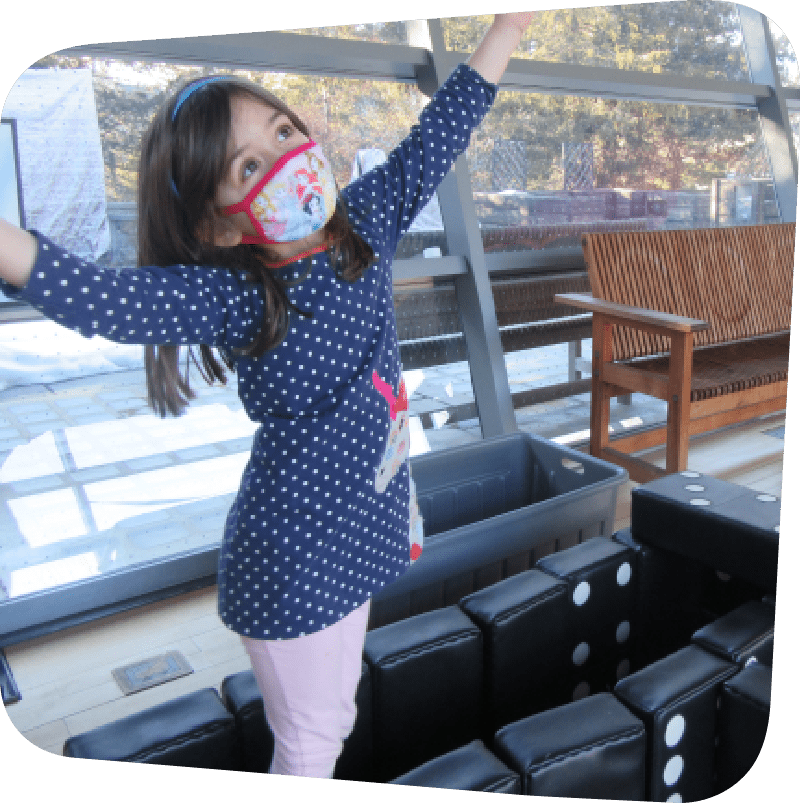 Child playing with dominoes in big games with arms in air