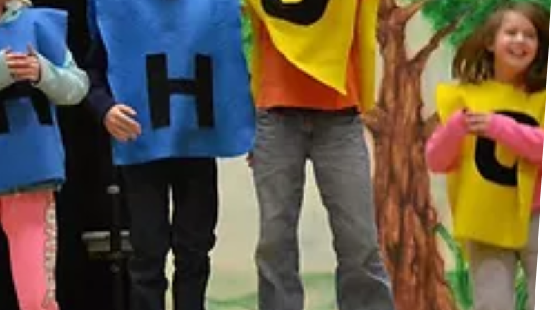 children in blue and yellow ponchos with letter H or O on them jumping up and down