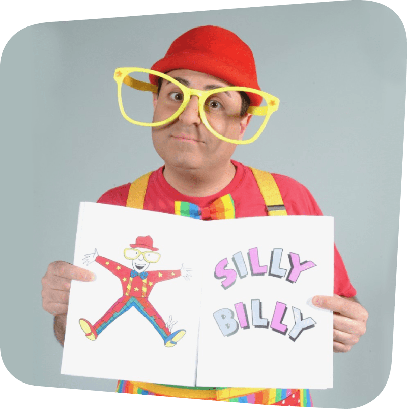 Silly Billy Magician wearing big yellow glasses and a red hat while holding a sign that reads "Silly Billy"
