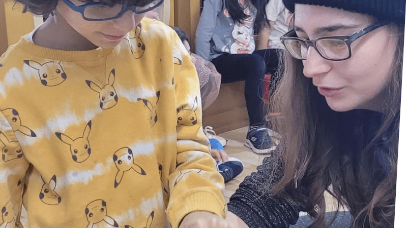 camper gently touching stick bug held by camp counselor