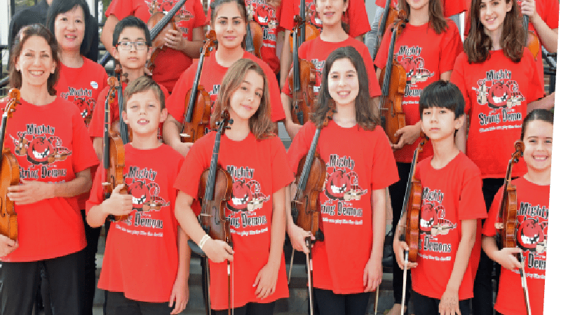 Depicts the Mighty String Demons youth violinist group. Children stand on the front steps of the Staten Island Children's Museum holding their violins. Standing with them are their director, Sanchie Bobrow holding a violin, and guest musicians Wenyi Lo and Kazuo Nakamura. All except Nakamura wear identical red Mighty String Demons shirts.