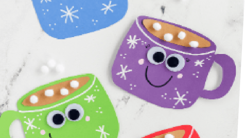 Four hot cocoa magnet crafts on a white countertop. Top left: blue mug with white snowflakes, fake brown "hot chocolate and fluffy white marshmallows" inside. Underneath, from right to left going down: purple, green, and red hot chocolate magnet mugs. The purple and green mugs have googly eyes and smiles.