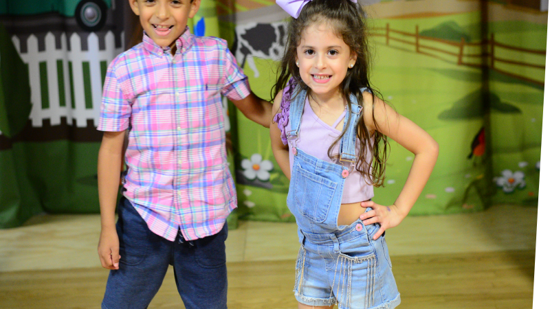 two children smiling standing on the stage in the Portia's Playhouse exhibit