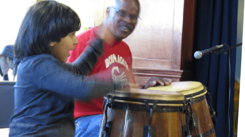 Smiling boy playing a large drum with his hands