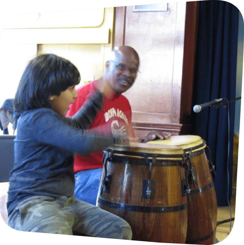 Smiling boy playing a large drum with his hands