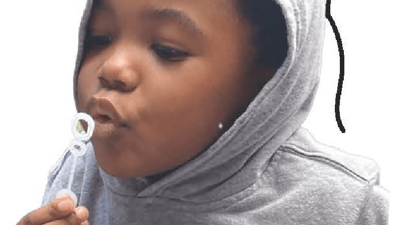 child in a grey hoodie blowing bubbles