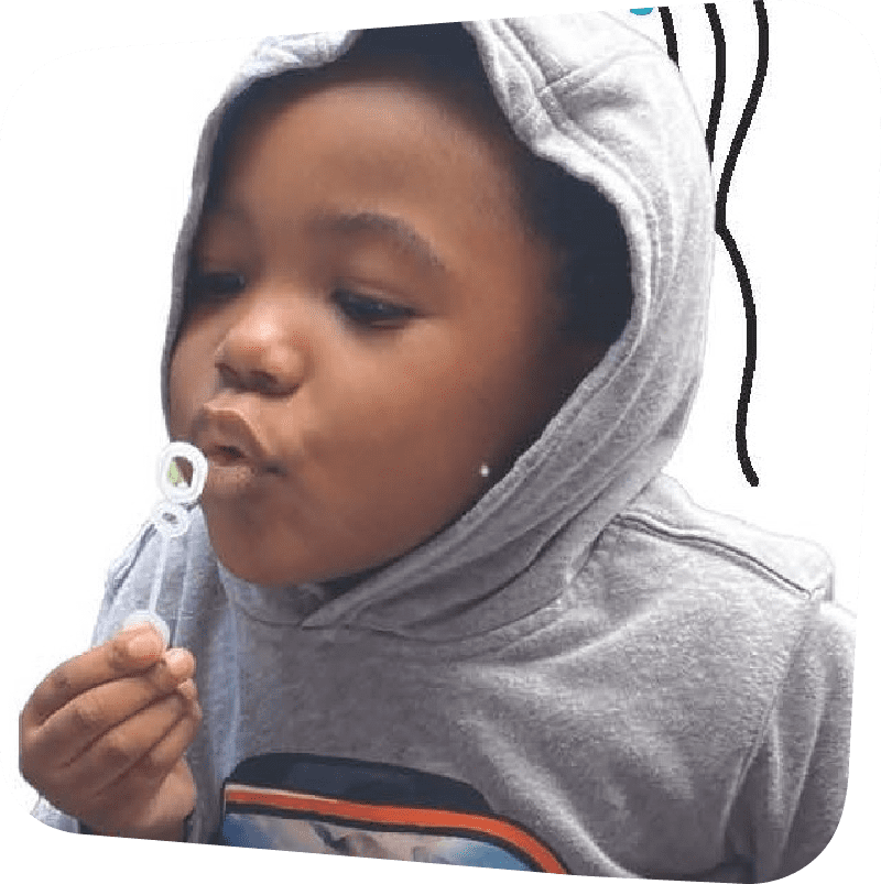 child in a grey hoodie blowing bubbles